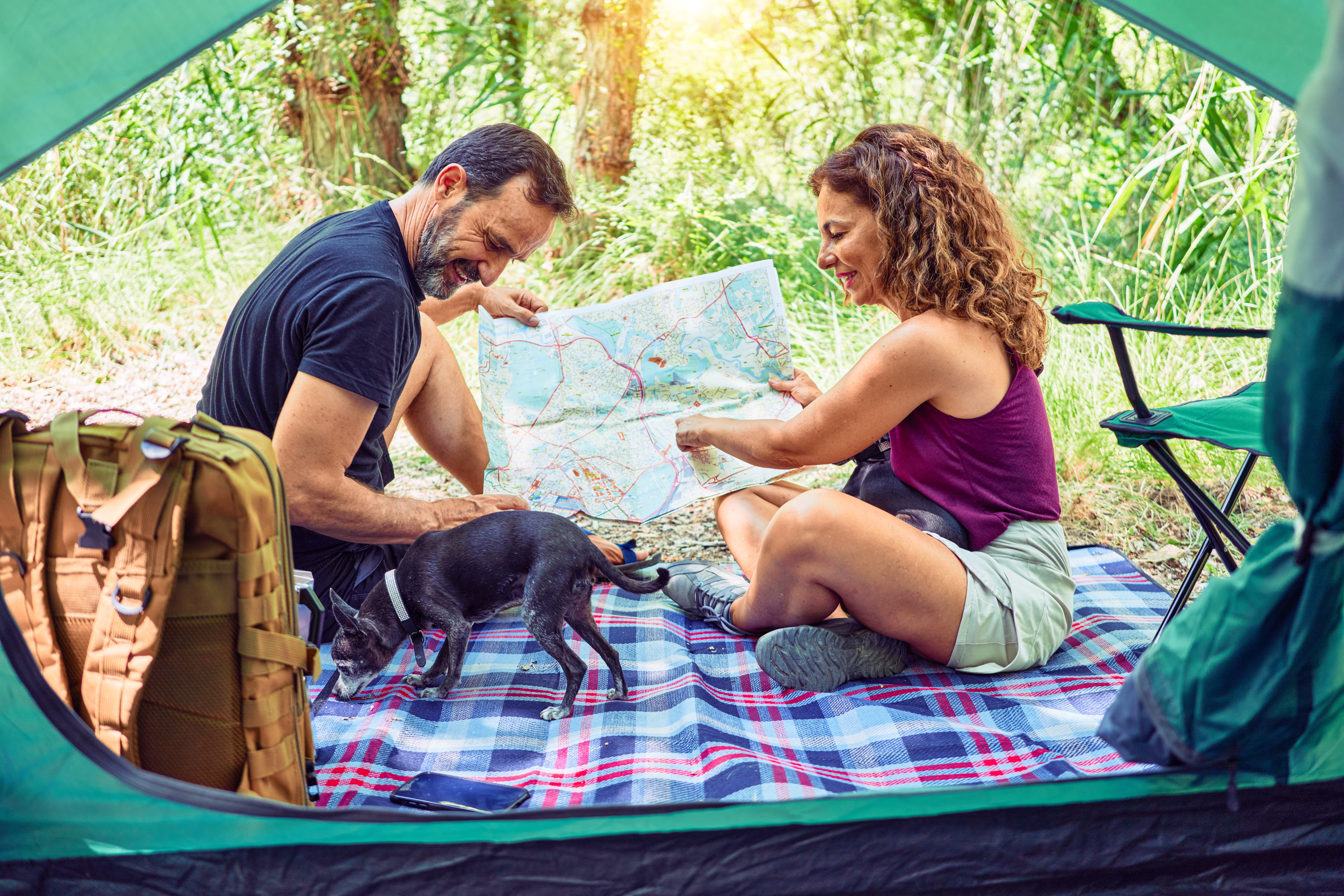 Couple planning a trip looking at a map with dog in tent in Colorado